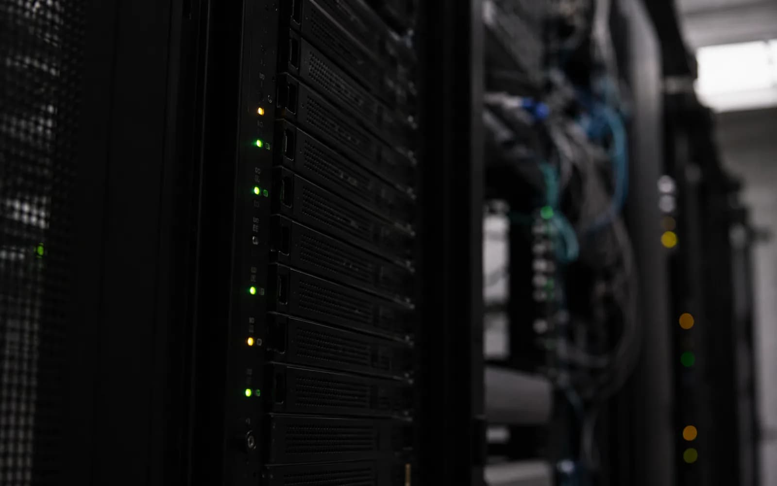Server-Rack im Detail mit grünen und amber Status-LEDs, ruhiges Wachsamkeits-Gefühl im halbdunklen Rechenzentrum
